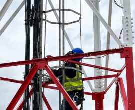 An engineer working on a cell tower to strengthen connectivity.