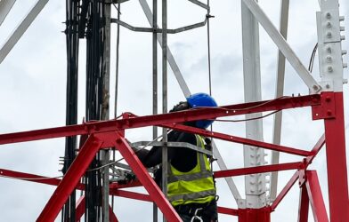 An engineer working on a cell tower to strengthen connectivity.