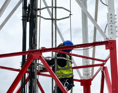 An engineer working on a cell tower to strengthen connectivity.