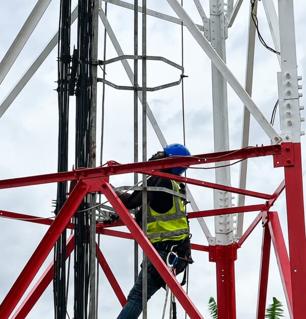 An engineer working on a cell tower to strengthen connectivity.