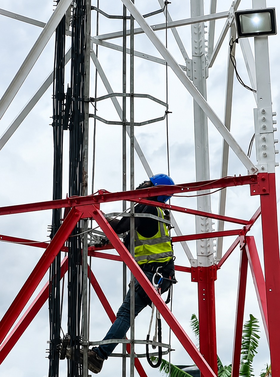 An engineer working on a cell tower to strengthen connectivity.